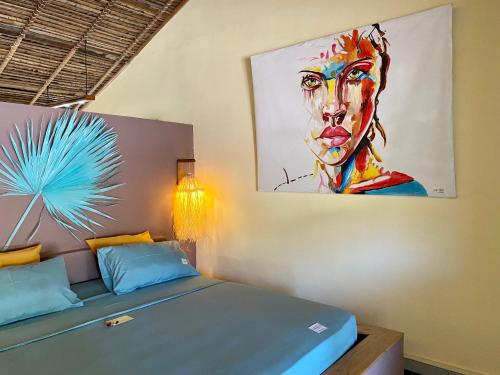 a bedroom with a bed with a painting on the wall at La perle rare de Nosy be in Ambatoloaka