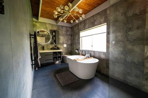 un bagno con vasca, lavandino e finestra di 4 Bedroom fun house - spa, sauna, fire pits & more a Healesville