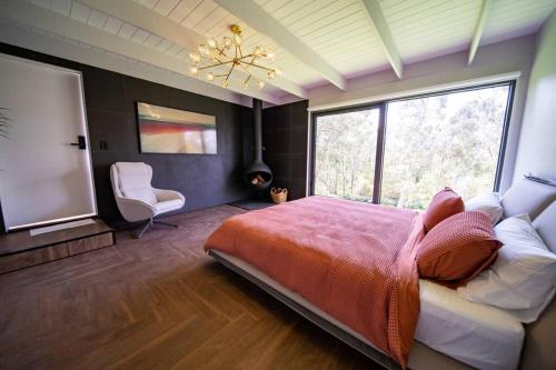 ein Schlafzimmer mit einem großen Bett und einem großen Fenster in der Unterkunft 4 Bedroom fun house - spa, sauna, fire pits & more in Healesville