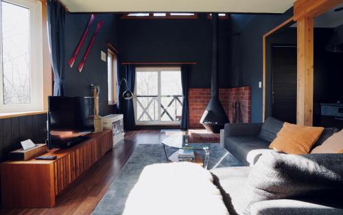 uma sala de estar com um sofá e uma televisão em Goodfellas Onsen House em Niseko