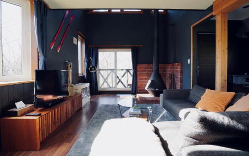 a living room with a couch and a tv at Goodfellas Onsen House in Niseko