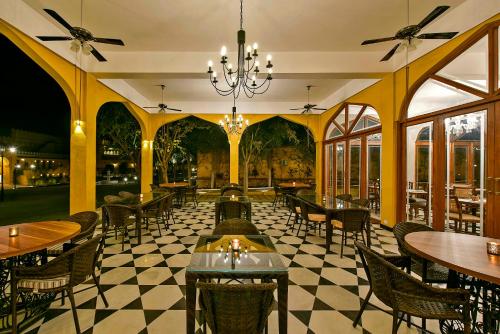 a restaurant with a checkered floor and tables and chairs at Gogunda Palace in Udaipur