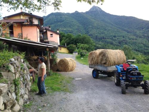 a man standing next to a tractor pulling a trailer with hay at Agriturismo Al Marnich in Schignano