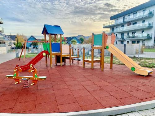un parque infantil con diferentes tipos de equipos de juego sobre un suelo de ladrillo en Widok na Morze Apartament przy plaży Premium by STAYLY, en Dziwnów