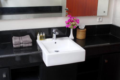 uma casa de banho com um lavatório branco e um vaso de flores em Villa Karingal em Senggigi