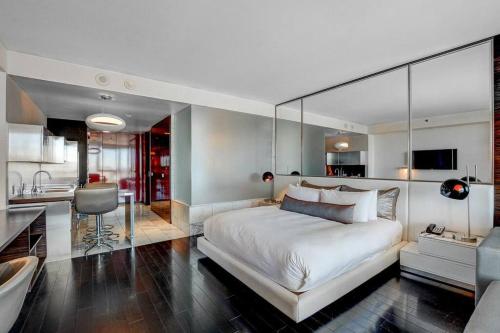 a bedroom with a large white bed and a kitchen at Strip View Luxury Studio No Resort Fee Palms Place in Las Vegas