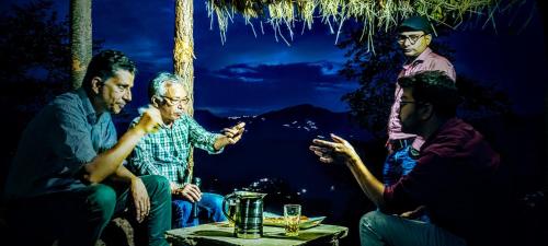 a group of men sitting around a table at night at The Chakras Valley Homestay in Almora