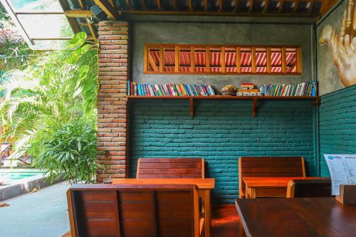 ein Restaurant mit Tischen und Stühlen und einem Bücherregal in der Unterkunft Pipes Hostel in Kuta Lombok