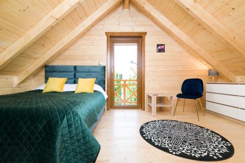 a bedroom with a green bed in a attic at ,,Morski Zakątek'' Domki całoroczne in Ustronie Morskie