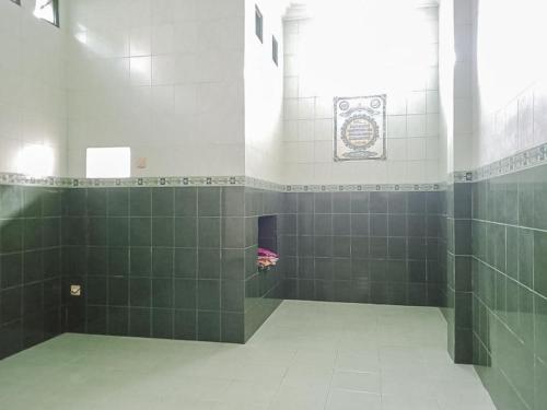 a bathroom with green tiled walls and a window at RedDoorz Syariah @ Hotel Sidomulyo Pacitan in Pacitan