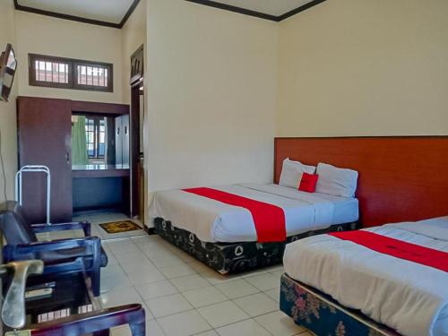 une chambre d'hôtel avec deux lits et une chaise dans l'établissement RedDoorz Syariah @ Hotel Sidomulyo Pacitan, à Pacitan