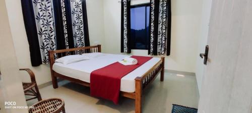a bedroom with a bed with a red blanket on it at Vagamon Misty Holiday Home in Vagamon