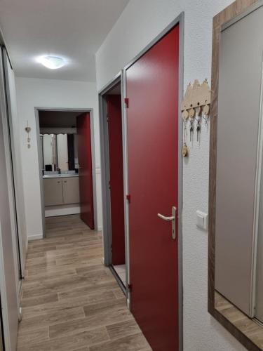 a hallway with a red door and a hallway with a kitchen at Agréable appartement de 6 pers au pieds des pistes ,wifi gratuit à Saint-Sorlin-d'Arves labelise 3 étoiles au gîte de France in Saint-Sorlin-dʼArves
