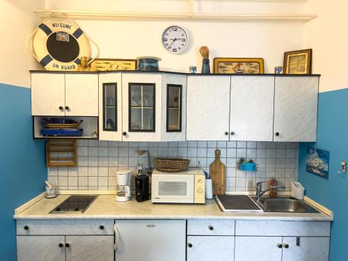 cocina con armarios blancos, fregadero y microondas en Apartma IVY, en Ankaran