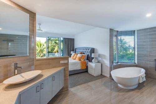 a bathroom with a tub and a sink and a bed at Yacht Harbour Tower 2, Hamilton Island - Million Dollar Views, Buggy & Valet Service in Hamilton Island
