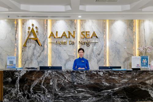 una mujer parada en un podio frente a una señal en Alan Sea Hotel Danang en Da Nang