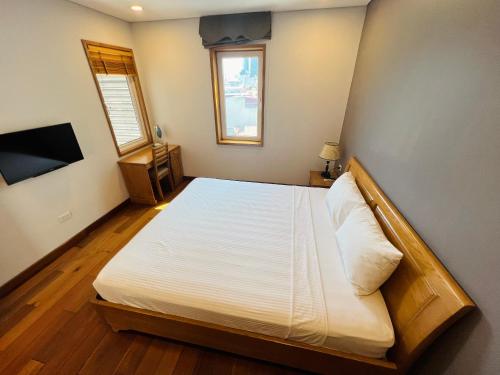 a bedroom with a large bed with white sheets and a window at HANA Stay Riverside in Hanoi