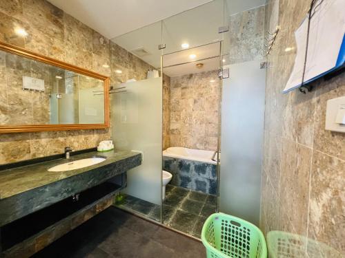 a bathroom with a sink and a mirror and a tub at HANA Stay Riverside in Hanoi
