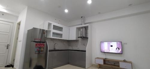 a kitchen with a refrigerator and a tv on a wall at Ha Long Homestay in Ha Long