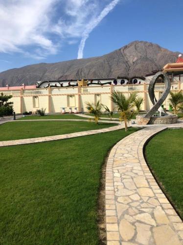 a building with a stone walkway in front of a lawn at Cloudy Cloud Farm Resort in Izkī