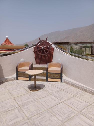 a patio with two chairs and a table and a wheel at Cloudy Cloud Farm Resort in Izkī