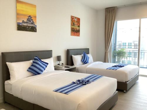 Cette chambre comprend 2 lits et une fenêtre. dans l'établissement Grandpa Resort Lamphun Chiangmai, à Ban Nong Pla Kho