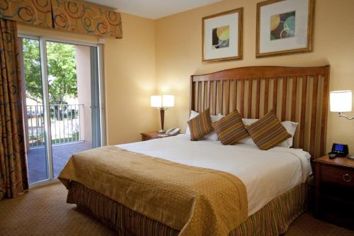 ポンパノビーチにあるClub Wyndham Palm-Aireの大きなベッドとバルコニーが備わるホテルルームです。