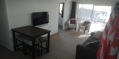 sala de estar con TV, mesa y sillas en Modest comfortable relaxed home away from home, en Rotorua