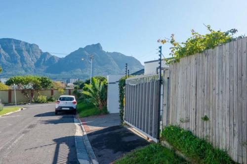 a white car parked in a driveway next to a fence at Centrally located modern 2-bedroom home & parking in Cape Town