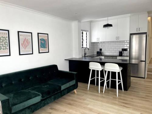 ein Wohnzimmer mit einem grünen Sofa und einer Küche in der Unterkunft Centrally located modern 2-bedroom home & parking in Kapstadt