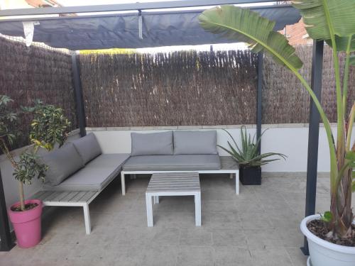 un patio con divano, tavolo e piante di Near beaches large private patio, aircon & community pool a Comarruga