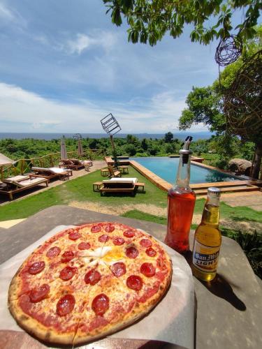 a pizza sitting on a table next to a bottle of beer at Nakabalo Guesthouse & Restaurant in Siquijor