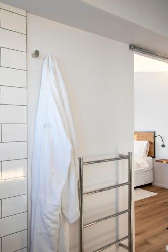 a white robe hanging on a wall in a bedroom at OnTheRocksBB Solar Powered Guesthouse and Ocean Lodge in Bettyʼs Bay