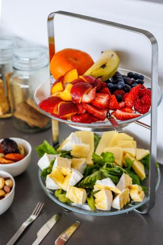 a three tiered plate of fruit and vegetables on a table at OnTheRocksBB Solar Powered Guesthouse and Ocean Lodge in Bettyʼs Bay