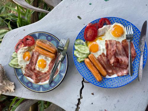 two plates of food with bacon eggs and vegetables at Happy Hippy House2 in Ko Chang