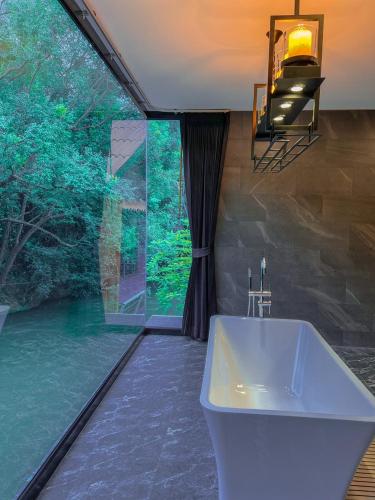a bathroom with a tub and a large window at Natthapon Resort Kaeng Kachan in Kaeng Krachan