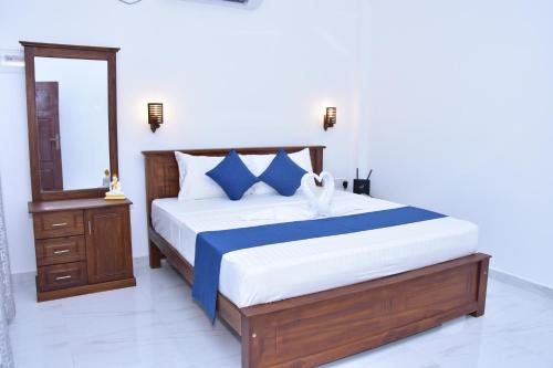 a bedroom with a bed with blue and white sheets at Ceylon Relax Villa in Moragalla