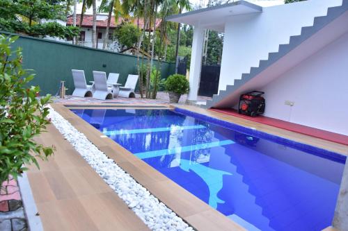 a swimming pool with a stair next to a house at Ceylon Relax Villa in Moragalla