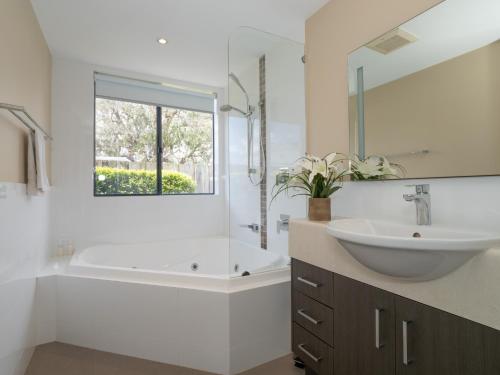 y baño blanco con lavabo, bañera y lavamanos. en Ocean View Executive Apartment 2, en Busselton