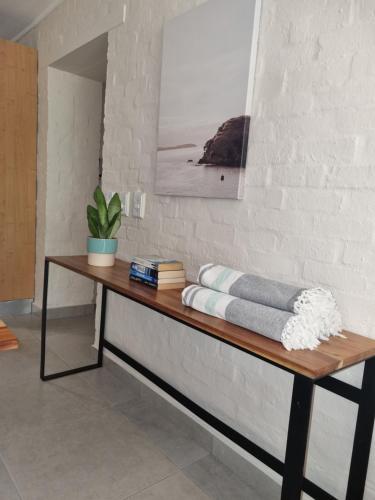 een houten tafel met een plant op een muur bij Beautiful apartment across from the beach in Kaapstad