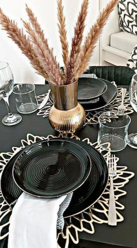 une table en noir et blanc avec des assiettes et un vase dans l'établissement Loft climatisé parking gratuit 5min gare, à Le Plessis-Bouchard
