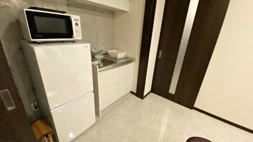 a small kitchen with a microwave on top of a refrigerator at Tabinoteitaku Okinawa Naha 2nd in Naha