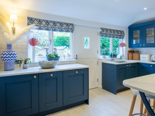 uma cozinha com armários azuis e bancadas brancas em Fairview Cottage em Moreton-in-Marsh