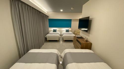 a hotel room with three beds and a television at Tabinoteitaku Okinawa Naha 2nd in Naha