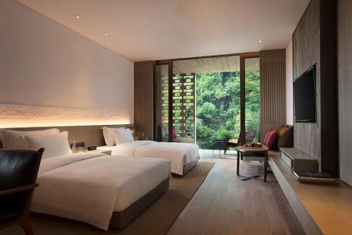 陽朔にあるYangshuo Sugar Houseのベッド2台とテレビが備わるホテルルームです。
