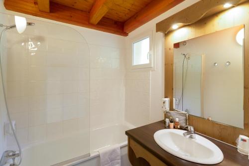 a bathroom with a sink and a tub and a mirror at Garden & City Evian - Lugrin in Lugrin