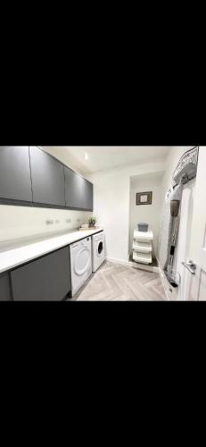 una cocina con electrodomésticos blancos y una silla. en Homely and Deceptively large city house, en Swansea