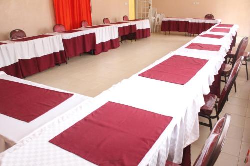una fila de mesas con manteles rojos y blancos en Good Morning Hotel Rongo, en Paulo