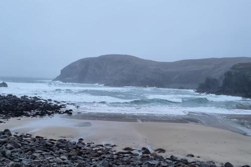 a beach with a rocky shore and the ocean at The back pod in Vatsker