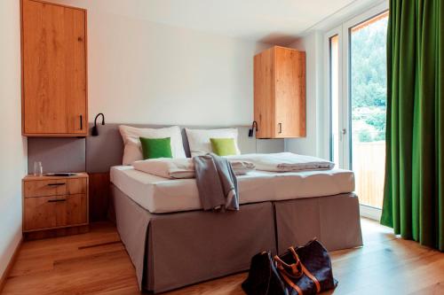 a bedroom with a large bed with green curtains at All-Suite Resort Ötztal in Oetz
